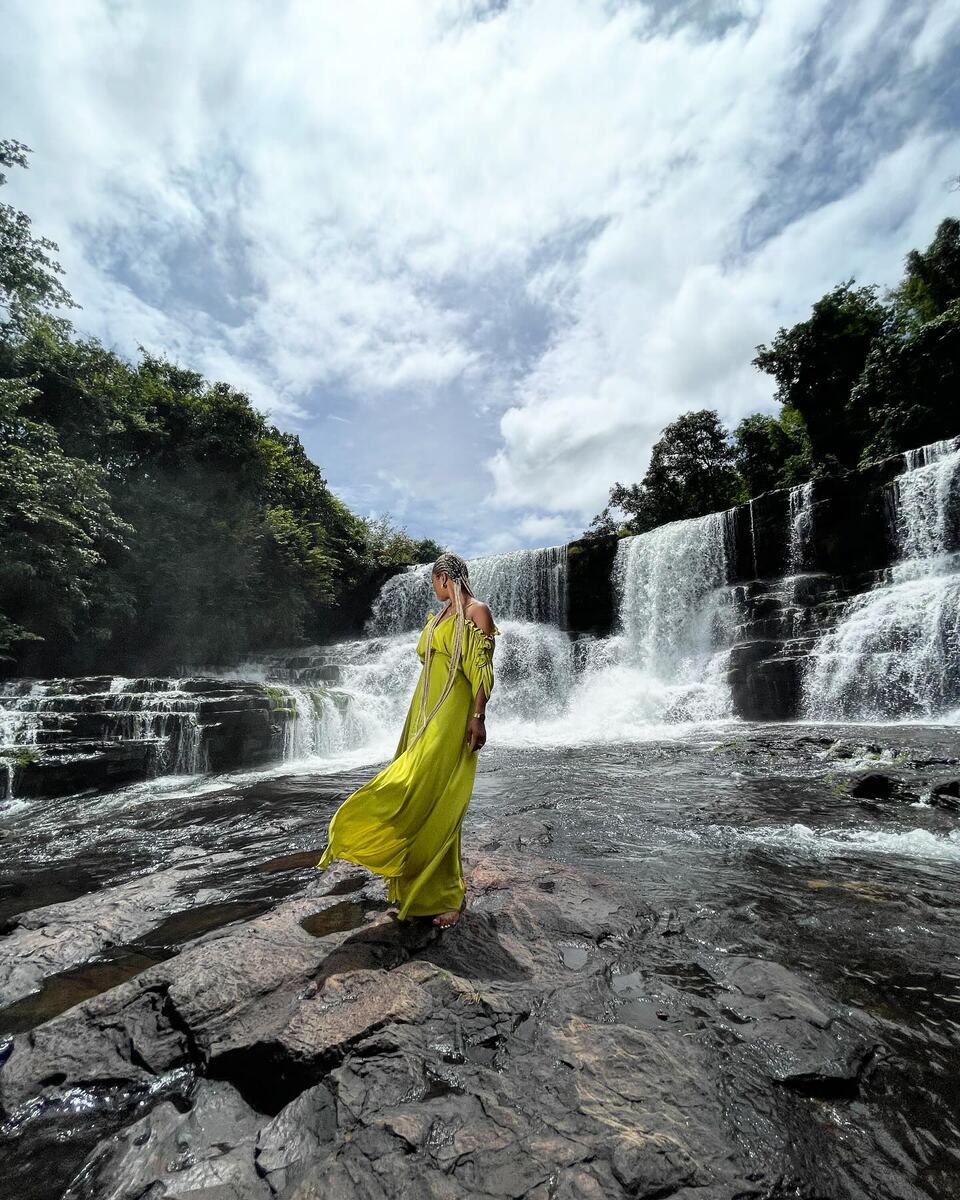 Amy Lucia Diop en robe fluide devant une cascade