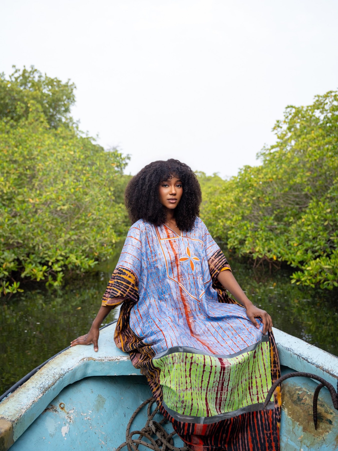 Amy Lucia Diop en boubou sur une pirogue dans la mangrove, en plein jour