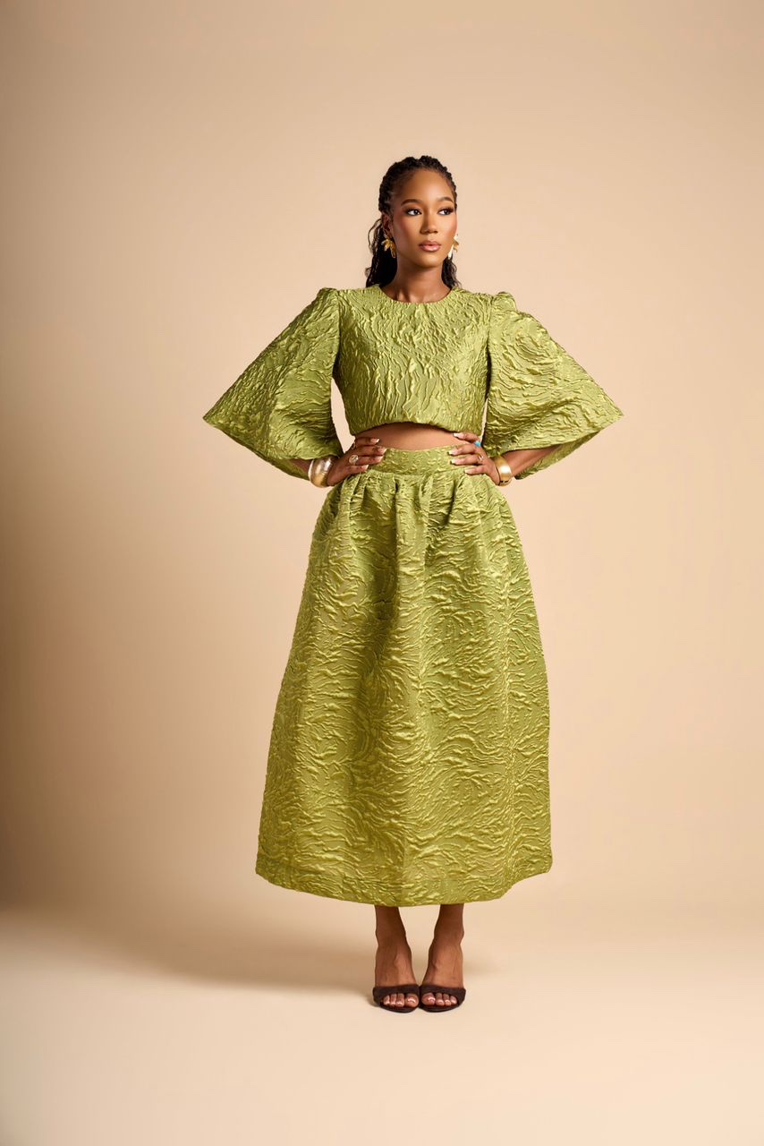 Amy Lucia Diop en ensemble vert anis en jacquard texturé, portrait en pied sur fond beige